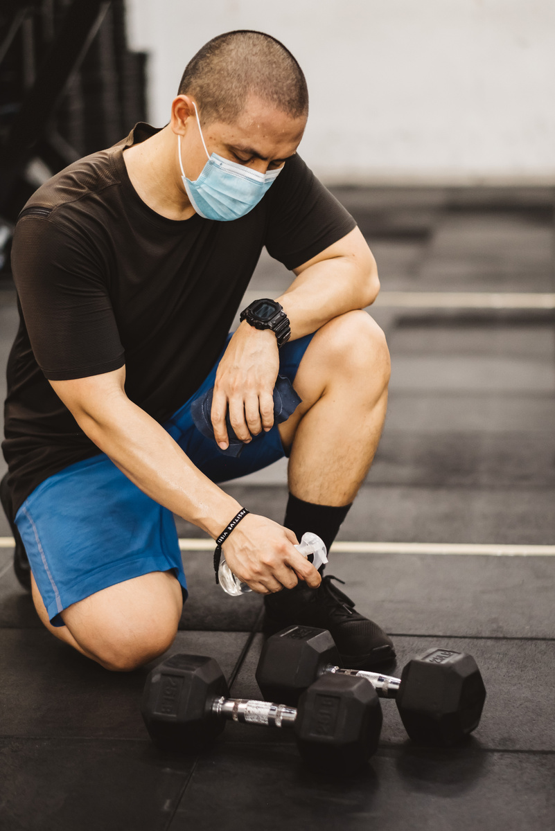 Man Wearing Face Mask Cleaning Gym Equipment